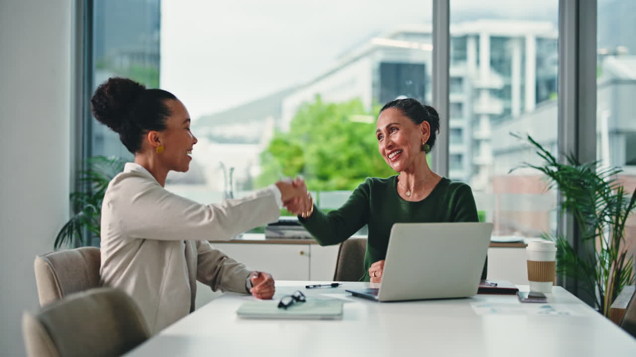 Two Businesswomen Shaking Hands in a Modern Office