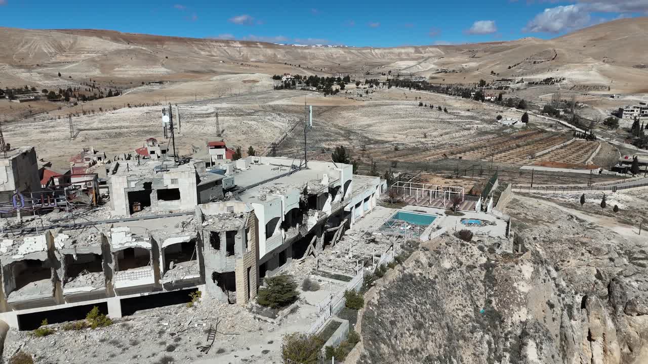 A wide aerial drone panorama of Ma'loula, Syria, highlighting the ancient village and the dramatic rocky cliffs of the Qalamoun range