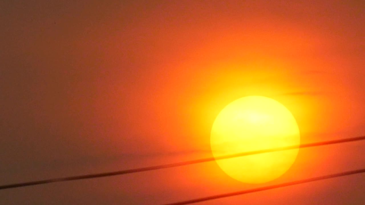puesta de sol naranja en el cielo rojo detrás del alambre