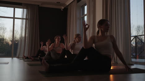 a group of women of different ages fat and thin practice yoga together with an instructor at sunset in slow motion.