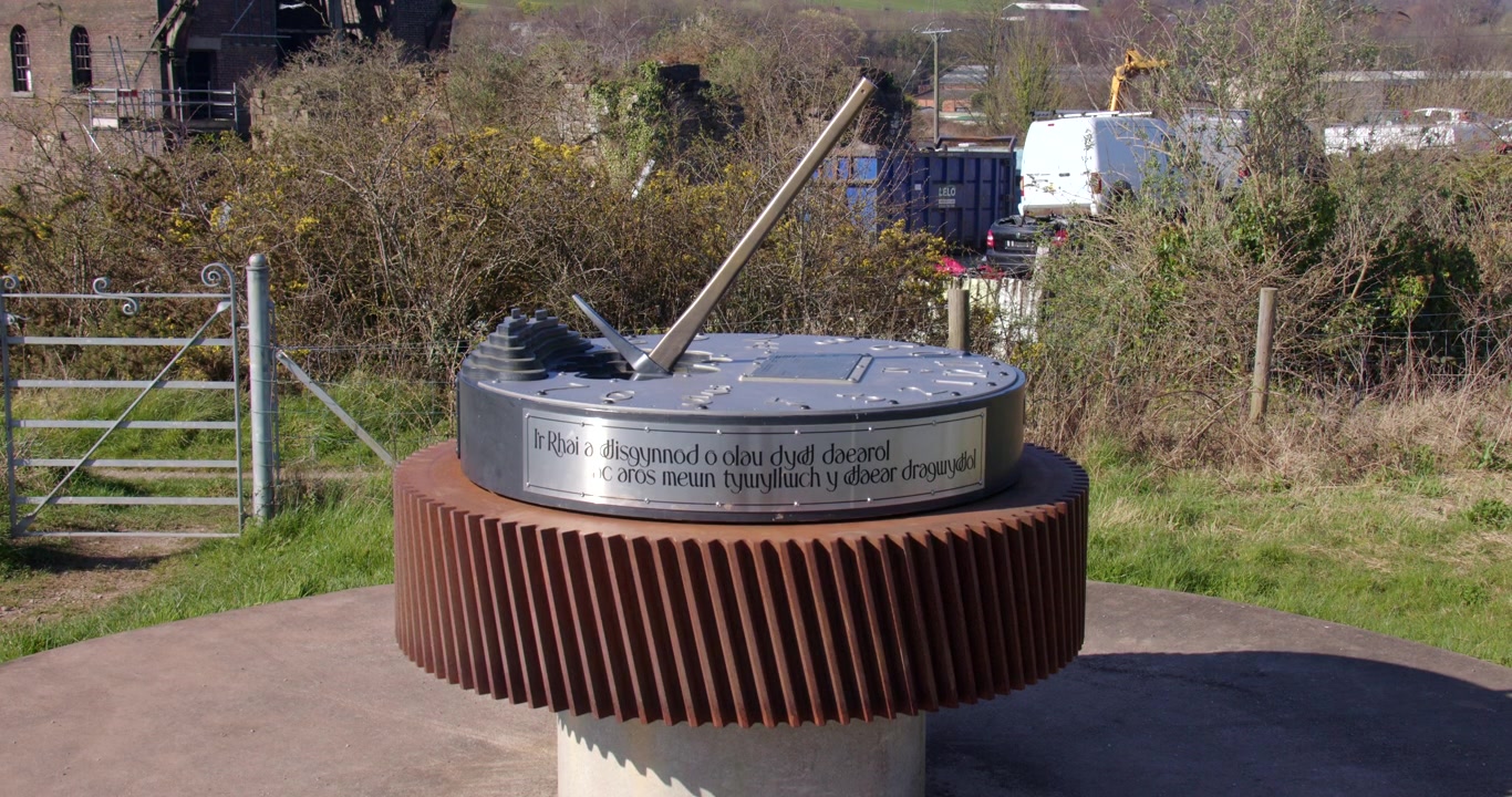 Inquadratura ampia della meridiana commemorativa mineraria di Bettisfield con un'iscrizione in lingua gallese