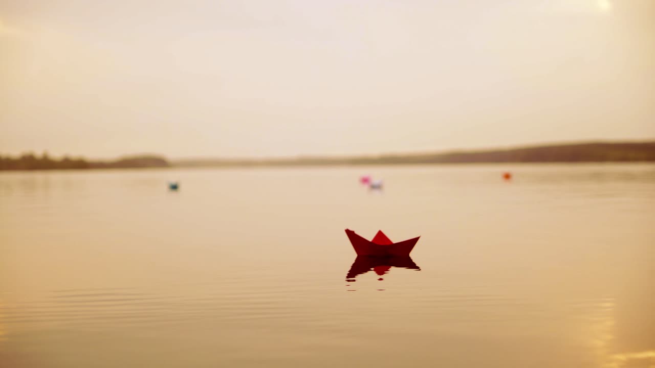 Paper boats floating in the river. Beautiful summer sunset. Origami.