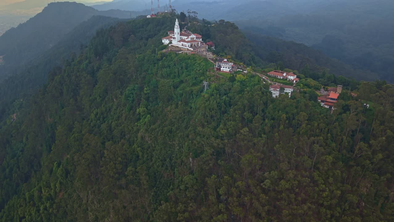 Reverse drone reveal uncovers the full Monserrate mountaintop sanctuary, opening into sweeping Andean ridgelines and untouched mountain scenery, a serene, isolated, and majestic high-altitude world