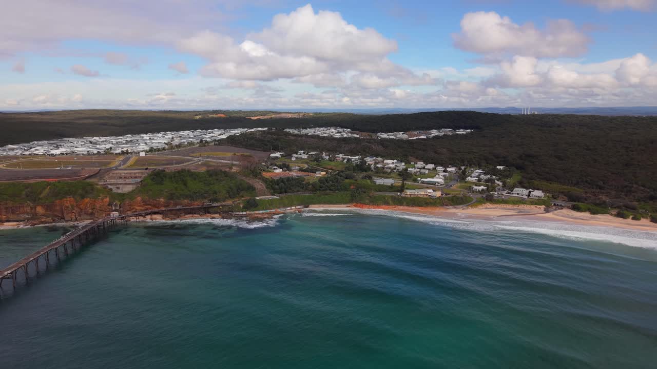 Wide aerial ascend of Catherine Hill Bay beach to jetty and coastline with blue sea in NSW