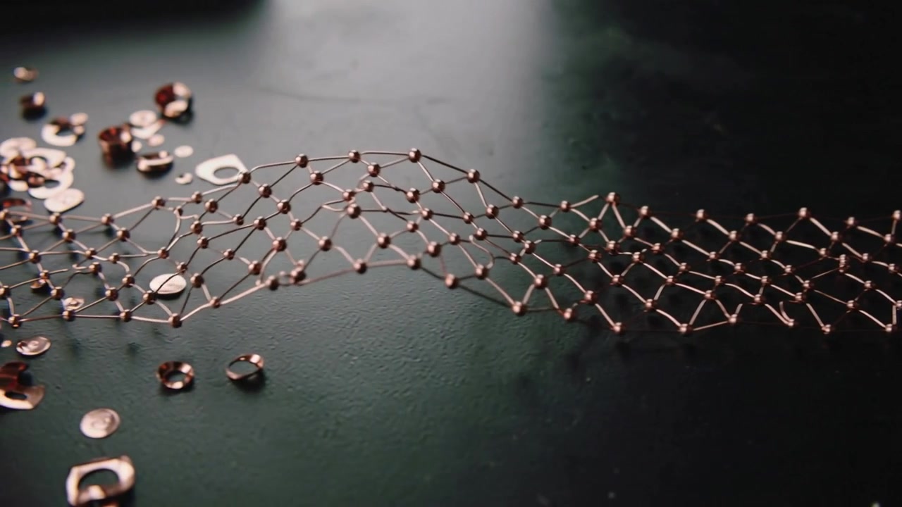 Lifting copper lattice with bead nodes undulating on dark bench, collecting sequins, clasp right