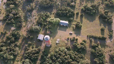 flying over an old and lost lighthouse at the coast of baltic sea - green trees country side of estonia in europe - nature helicopter flyover establishing shot summer 2022 - bird view