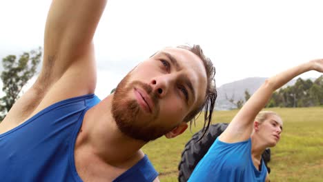 hombre y mujer en forma realizando ejercicios de estiramiento durante una carrera de obstáculos