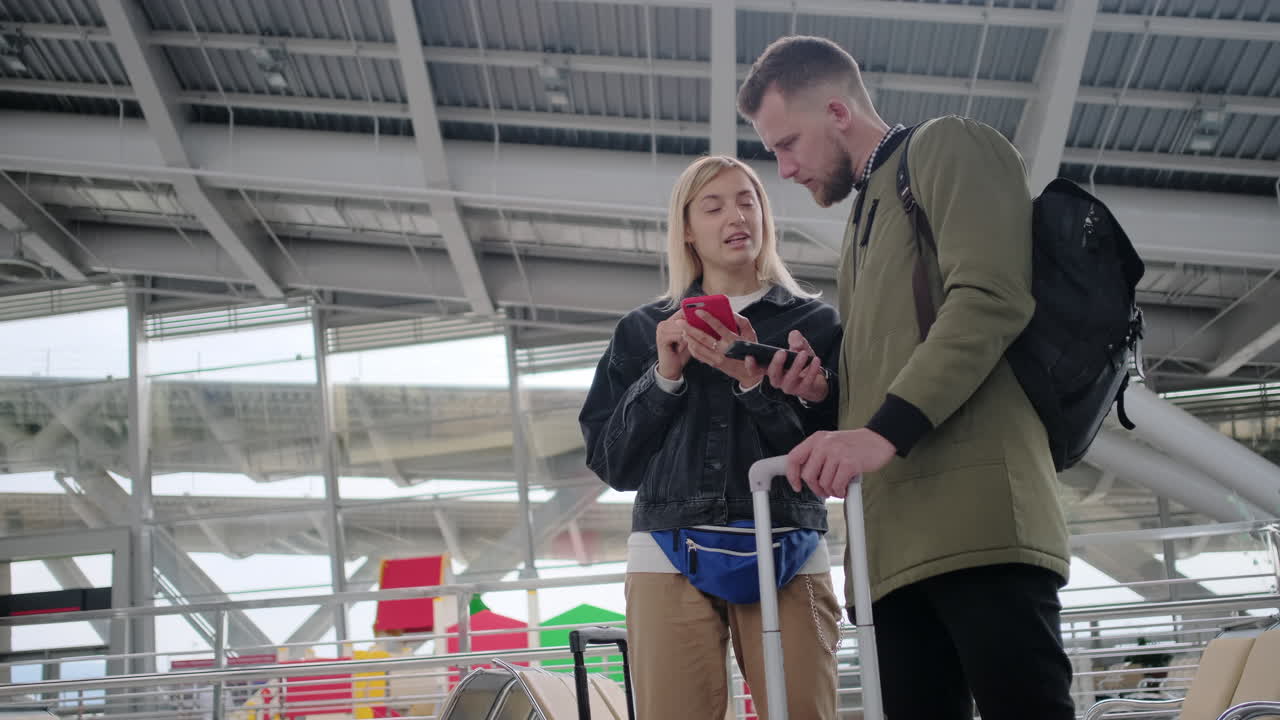 pareja usando teléfonos inteligentes en una terminal del aeropuerto