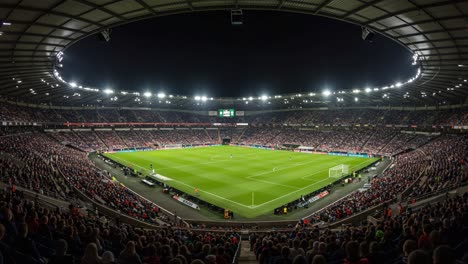 Captivating Nighttime Football Match Atmosphere in a Packed Stadium with Spectators Excitedly Watching the Game Under Bright Lights