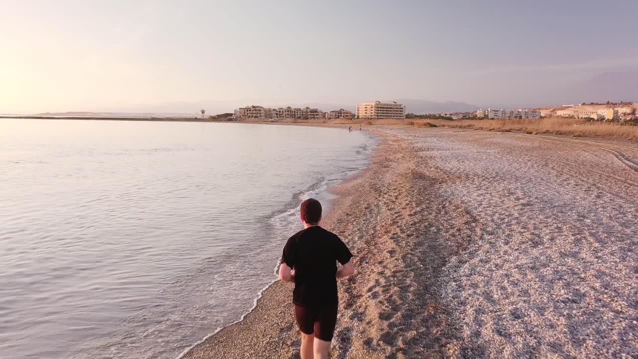 Young athlete runner man with fit strong body training on beautiful sunset at beach