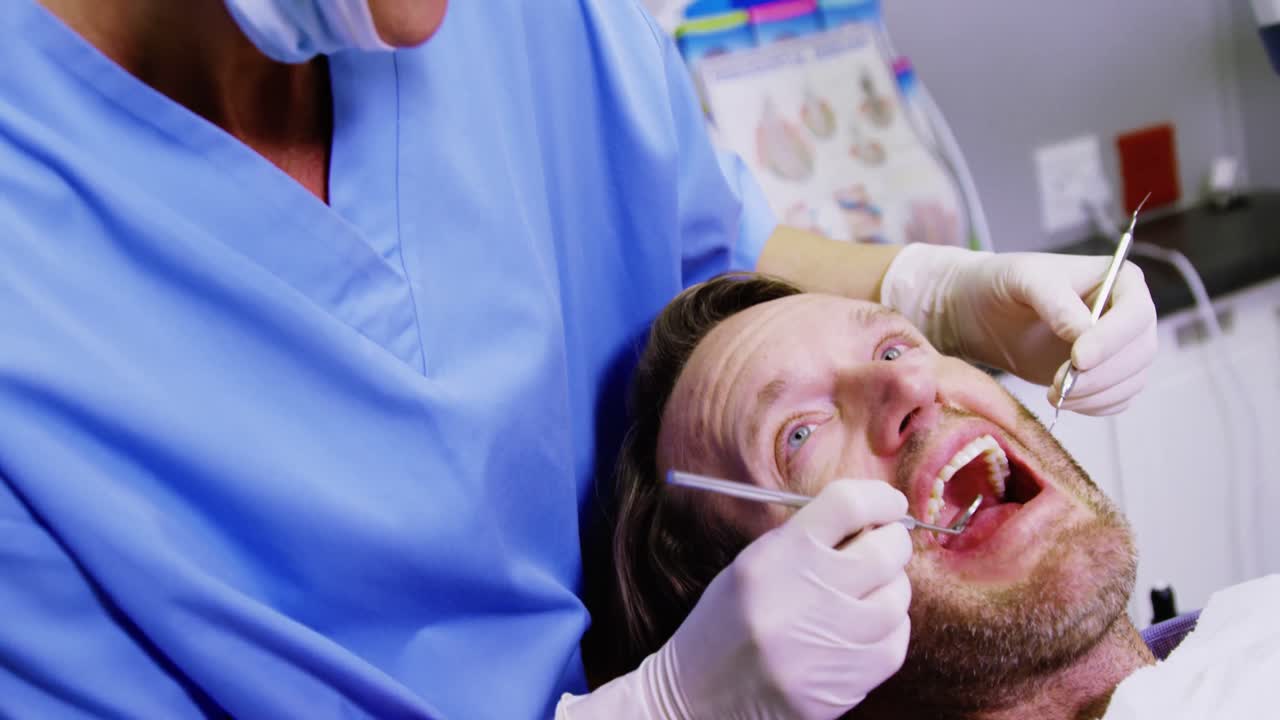 dentista examinando a un paciente masculino con herramientas dentales