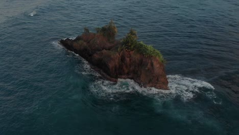 waves splashing on the rocky lost island in the middle of the ocean in puerto viejo, costa rica - aerial shot