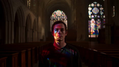 man illuminated by stained glass light in a church