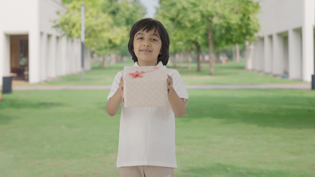 Anak laki-laki India yang bahagia memberikan hadiah di taman