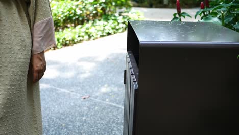 women hand throwing an empty plastic water bottle in the garbage trash or bin,