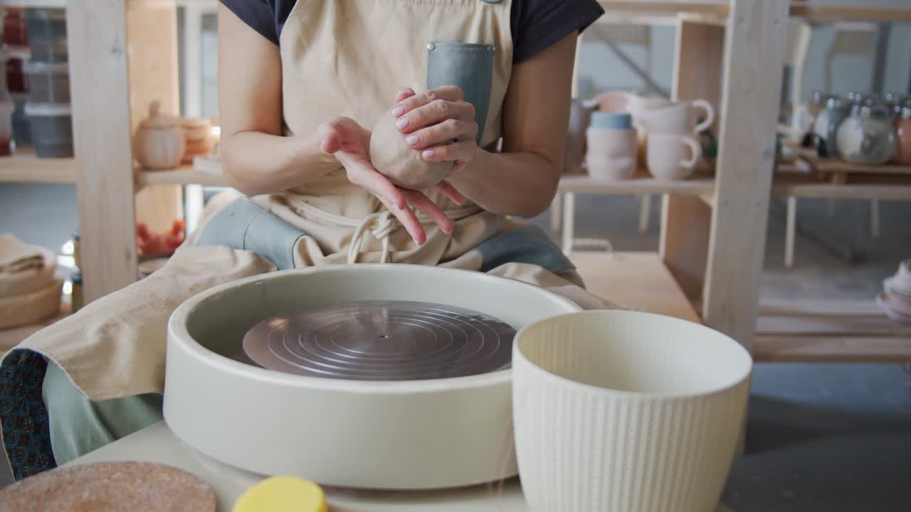 여성 도자기는 도자기 바에서 점토로 일을 시작합니다.