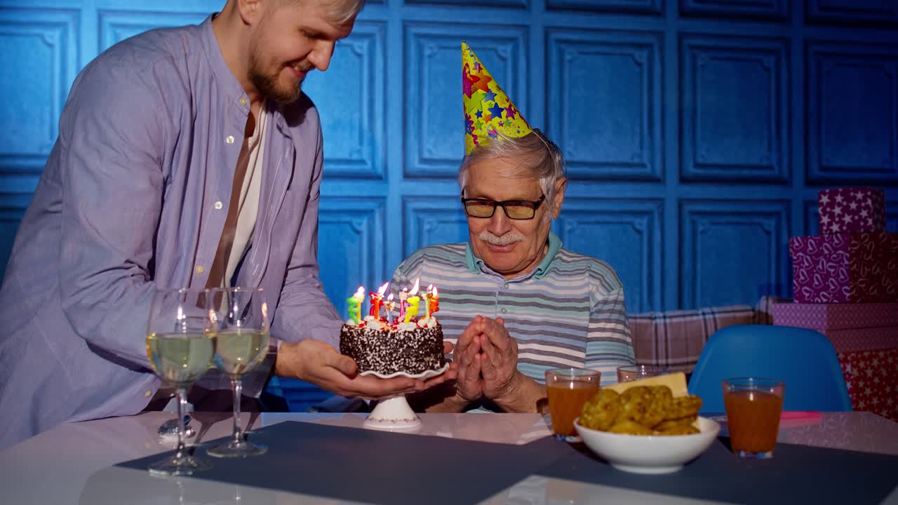 gran familia celebrando el cumpleaños del abuelo mayor, haciendo un deseo y soplando velas en casa