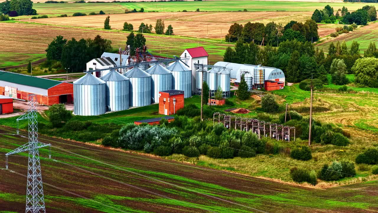 Ein lebendiger Bauernhof mit Silos und Feldern unter einem bewölkten Himmel