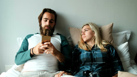 couple using mobile phone on bed at home 4k