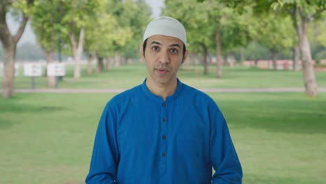 serious muslim man talking to the camera in park