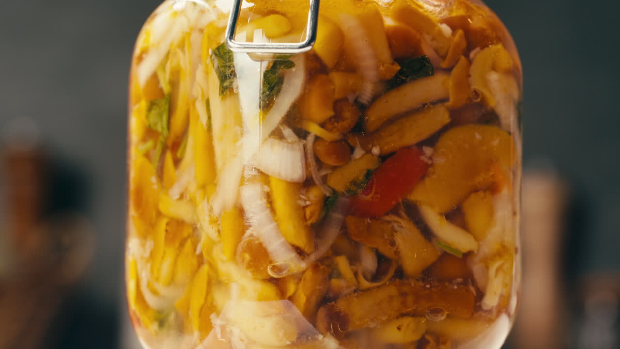 Primo piano di funghi gialli fermentati con cipolla in barattolo. Conservazione di verdure in barattoli di vetro. Funghi conservati per fermentazione con spezie.