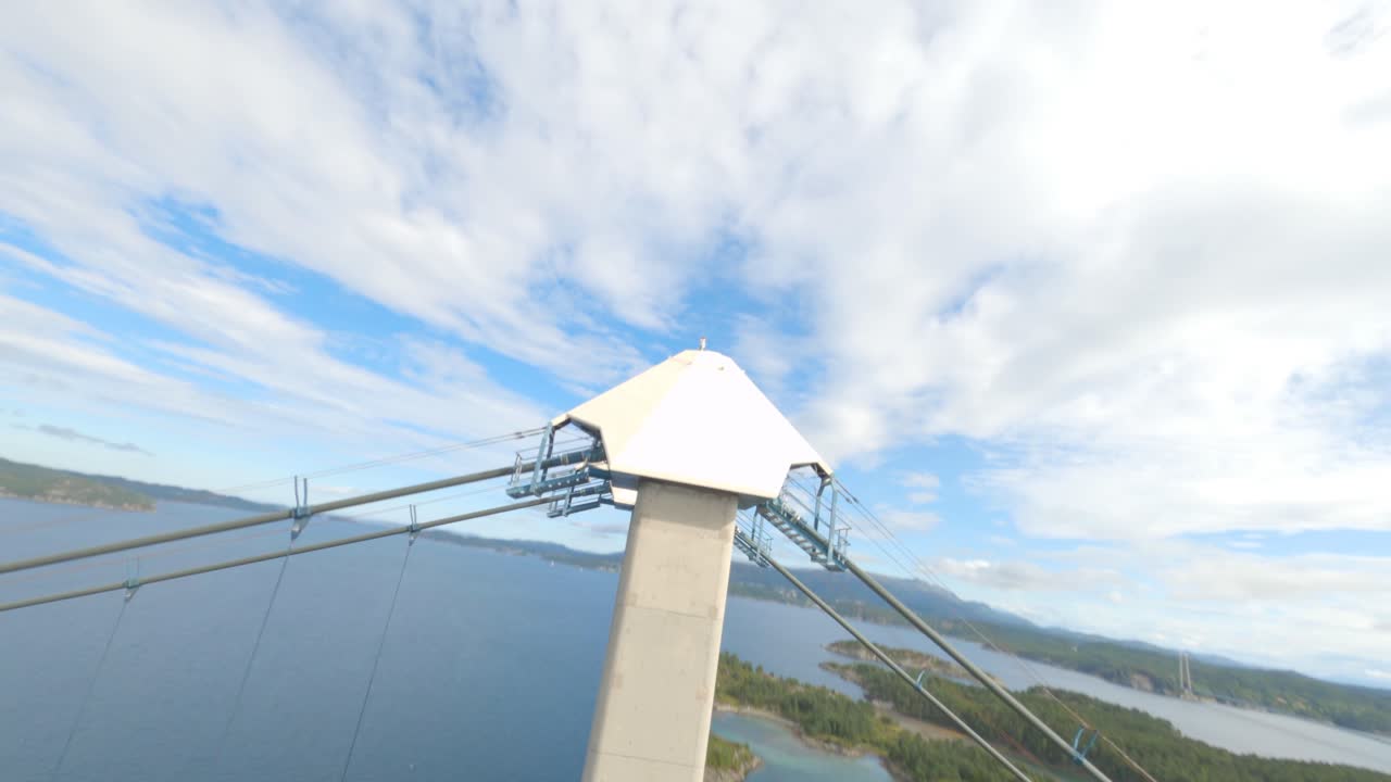 White pillar of Bomla suspension bridge in Norway, ascending FPV drone view