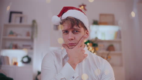 Suspicious-man-with-hand-on-chin-wearing-Santa-hat-at-home