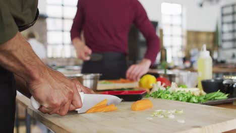 Mixed-race-male-chef-cutting-carrots-in-kitchen