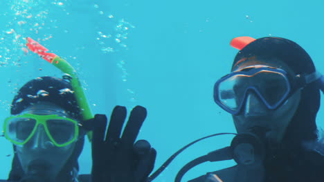 couple in scuba diving making ok sign with hands