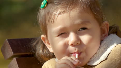 little girl eating lollipop in a park - face close-up