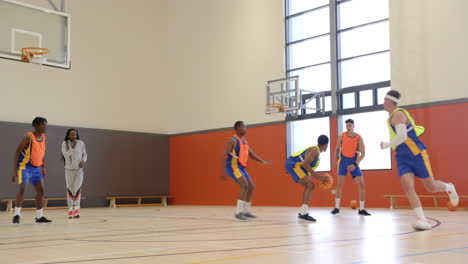 playing basketball in gym, team practicing with coach observing from sidelines