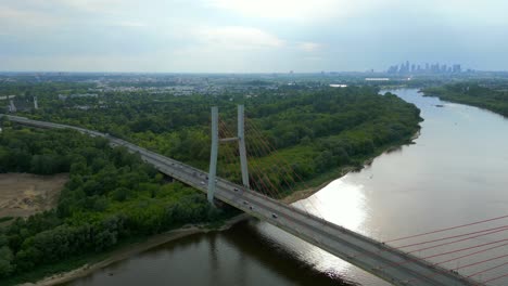 aerial panning shot of traffic on siekierkowski bridge with skyline of warsaw in background