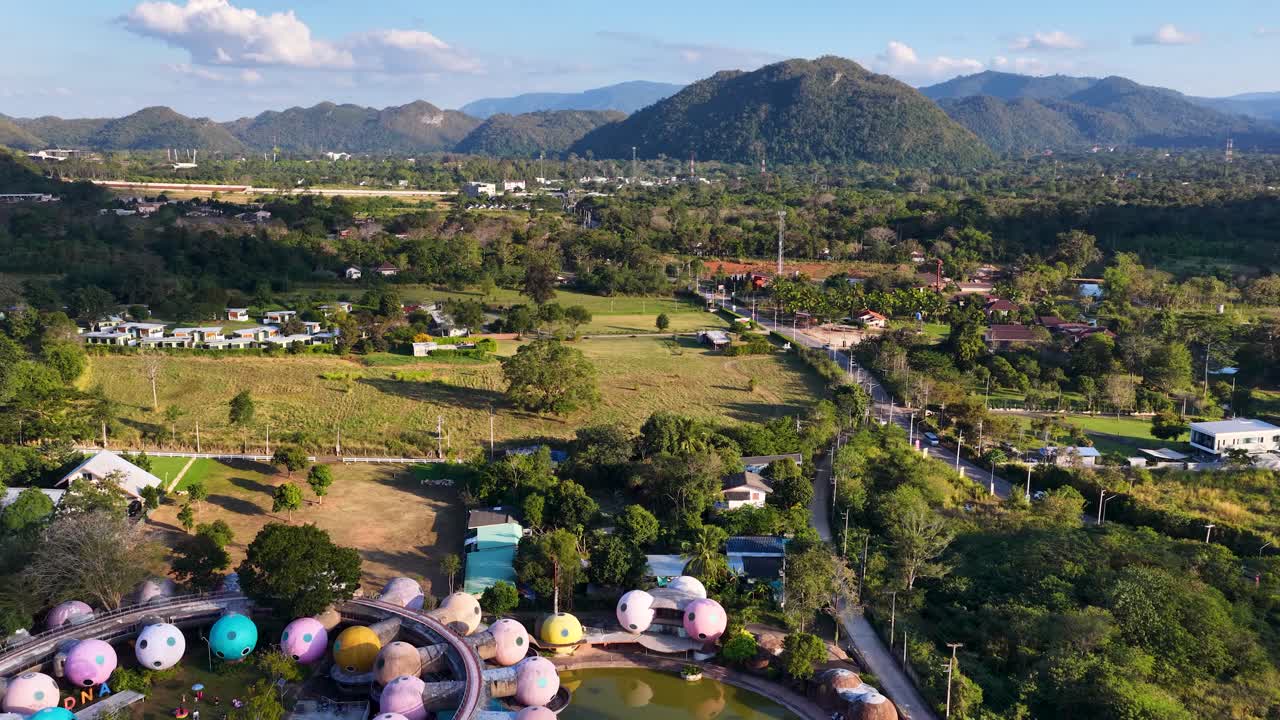 Uma filmagem de drone em alta altitude revela uma arquitetura de domo vibrante aninhada em paisagens montanhosas tropicais exuberantes