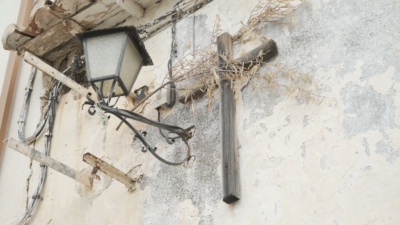 Old street lamp and cross on a weathered wall