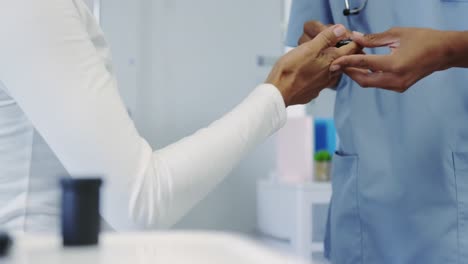 nahaufnahme einer afroamerikanischen ärztin, die den zuckerspiegel einer weiblichen patientin in einer krankenhausstation überprüft