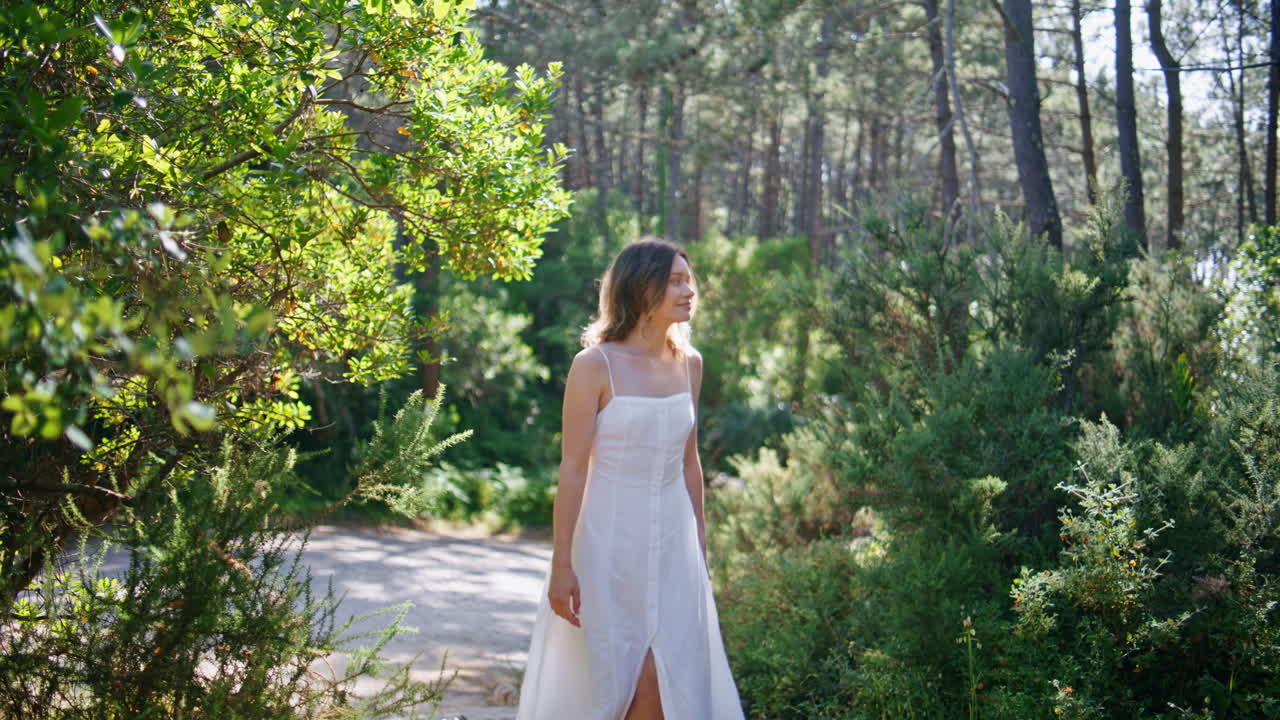 Serene woman walking garden in dress. Carefree girl stepping pathway nature