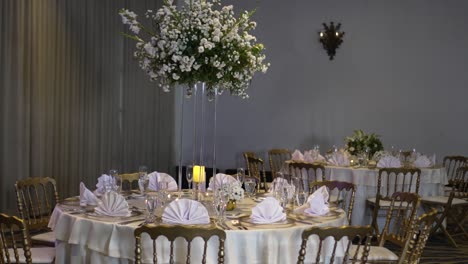 round table decorated with a tall centerpiece of white gypsophila paniculata flowers, in the hotel's event room for the wedding reception