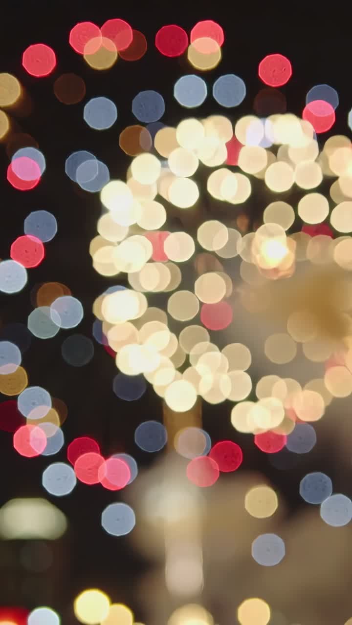 Lodret video: Affyring af blus, der sender bokeh over nattehimlen med røgsøjle og bylys til venstre