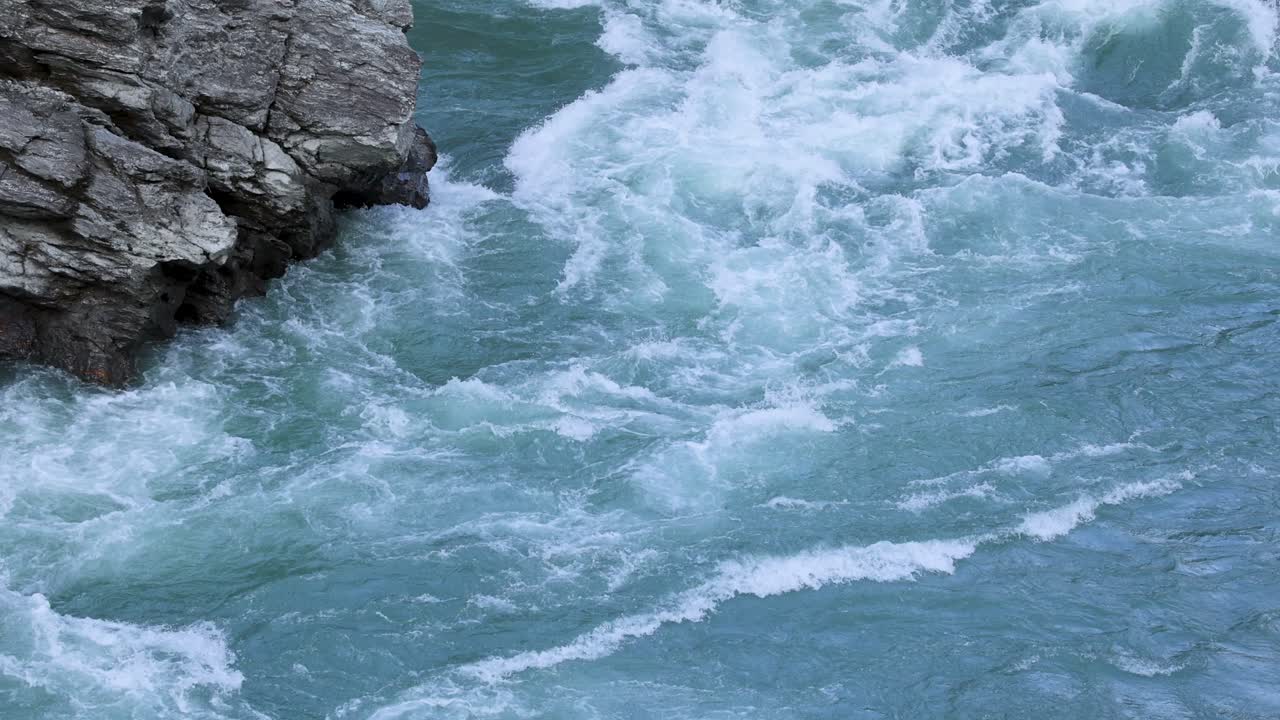 Dynamic river rapids cascade over rocky cliffs in Queenstown, New Zealand, captured with natural lighting and steady camera work