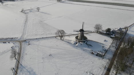 high angle aerial overview of traditional windmill in snow covered rural landscape