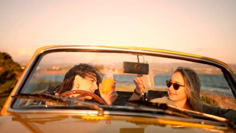 women with soda relaxing in retro convertible car at beach