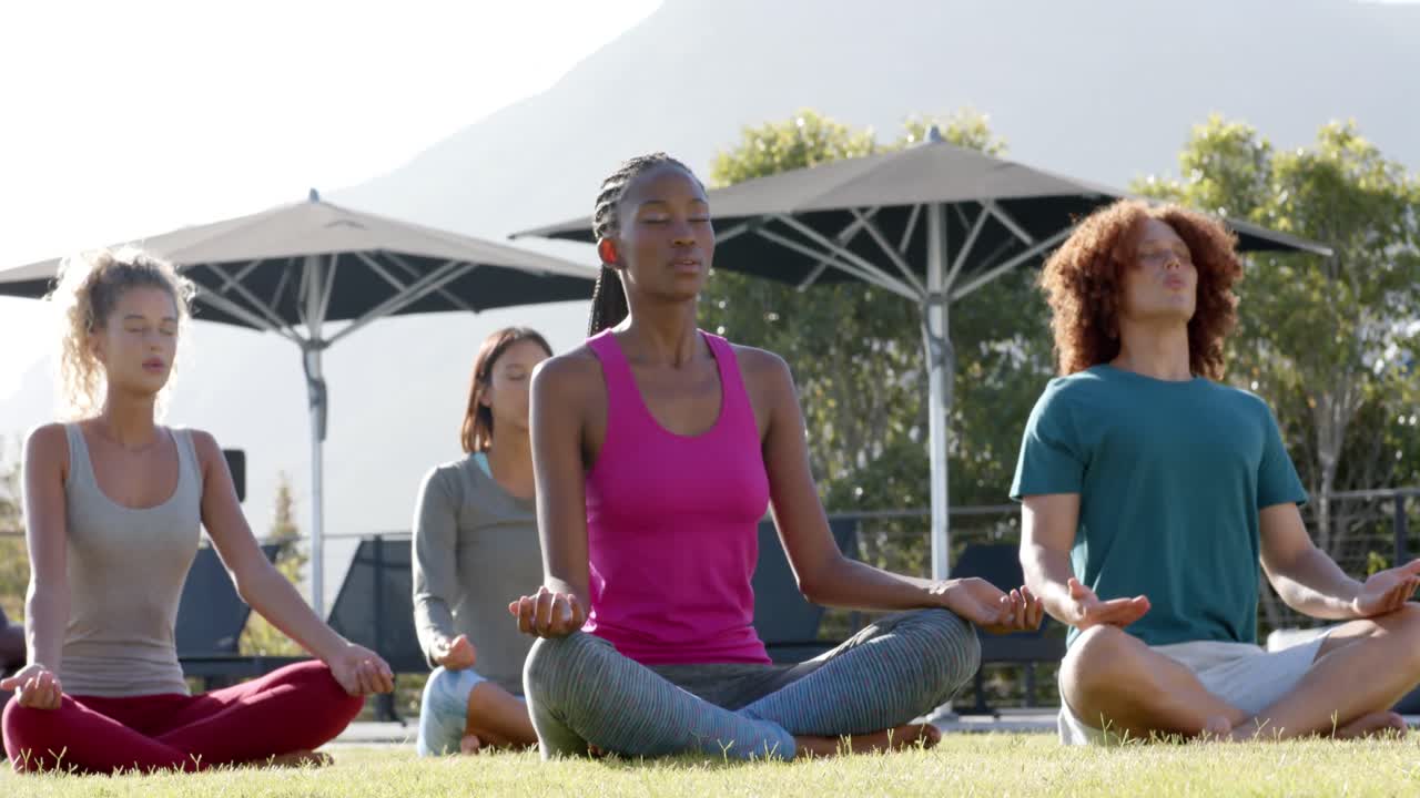 amigos diversos practicando meditación de yoga juntos sentados en un jardín soleado, cámara lenta