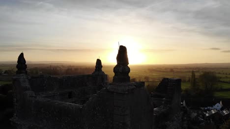 Aerial-panning-right-shot-of-the-top-of-a-church-with-an-beautiful-sunset-backdrop