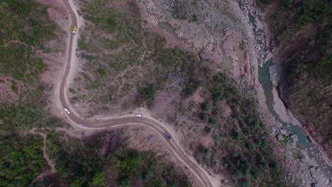 toma superior de un camino accidentado con río y tráfico en el bosque