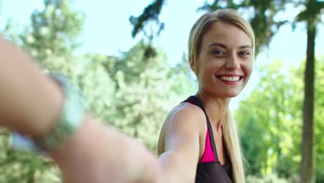 happy woman holding male hand and leading boyfriend in summer park