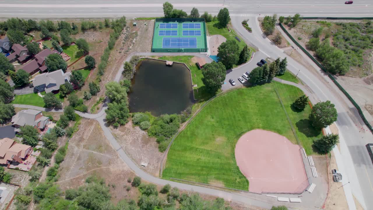 Aerial overview of Trent Park in Silverthorne Colorado. Camera flies over baseball field, a pond and tennis court.
