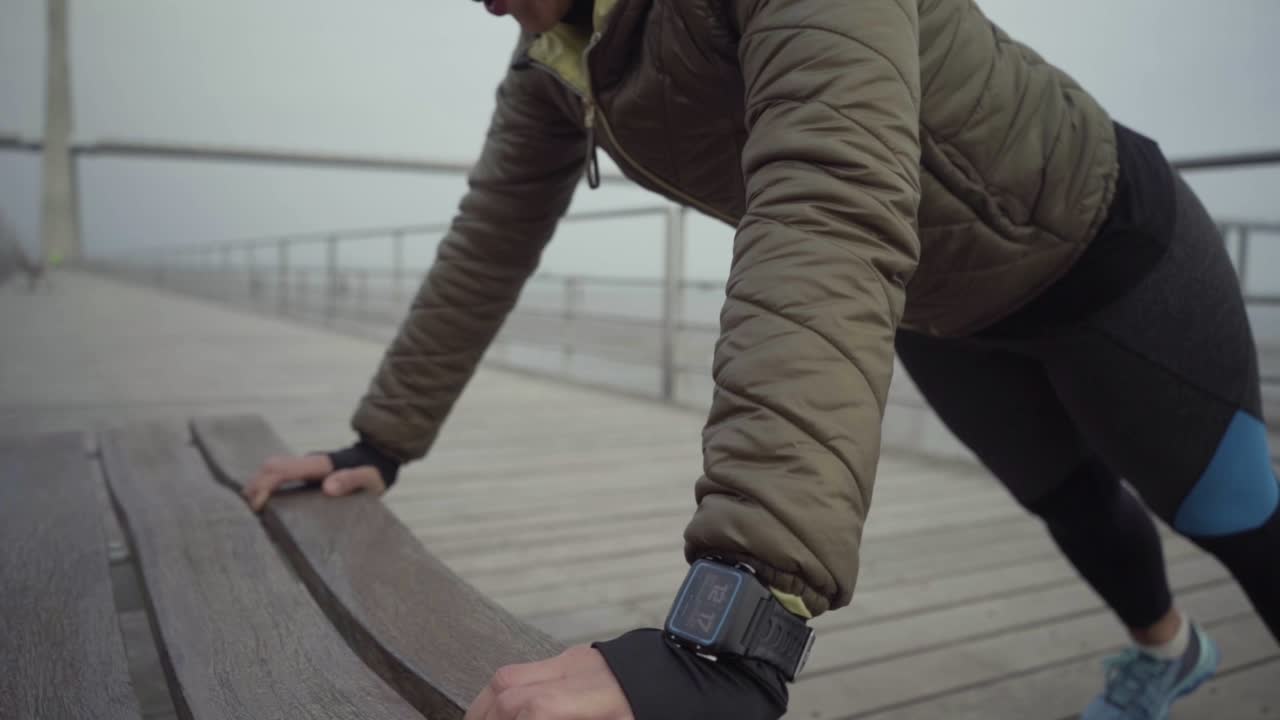 улыбающаяся индусская женщина делает отжимания с деревянной скамейки