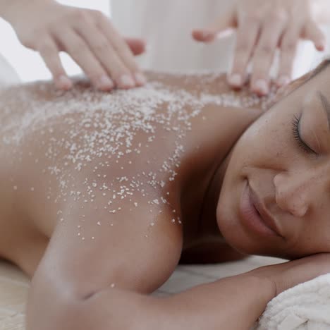 mujer recibiendo un tratamiento de exfoliación con sal