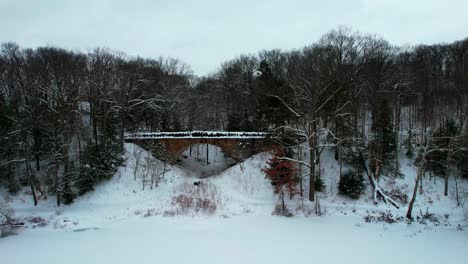 side view, aerial footage of parapet bridge in mill creek during winter season