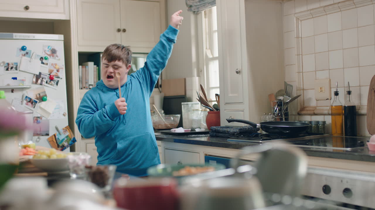 happy teenage boy with down syndrome dancing in kitchen having fun celebrating funny dance enjoying weekend at home
